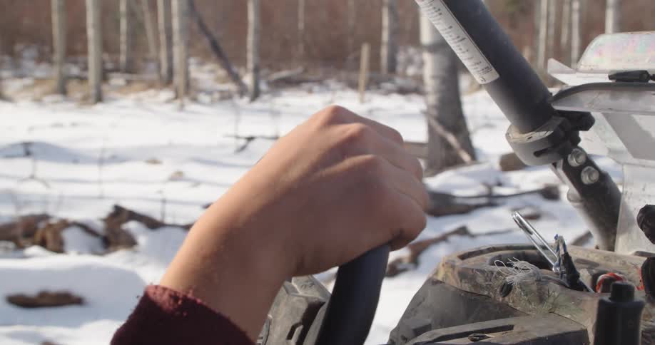 A person is driving the all terrain vehicle through the snow covered forest