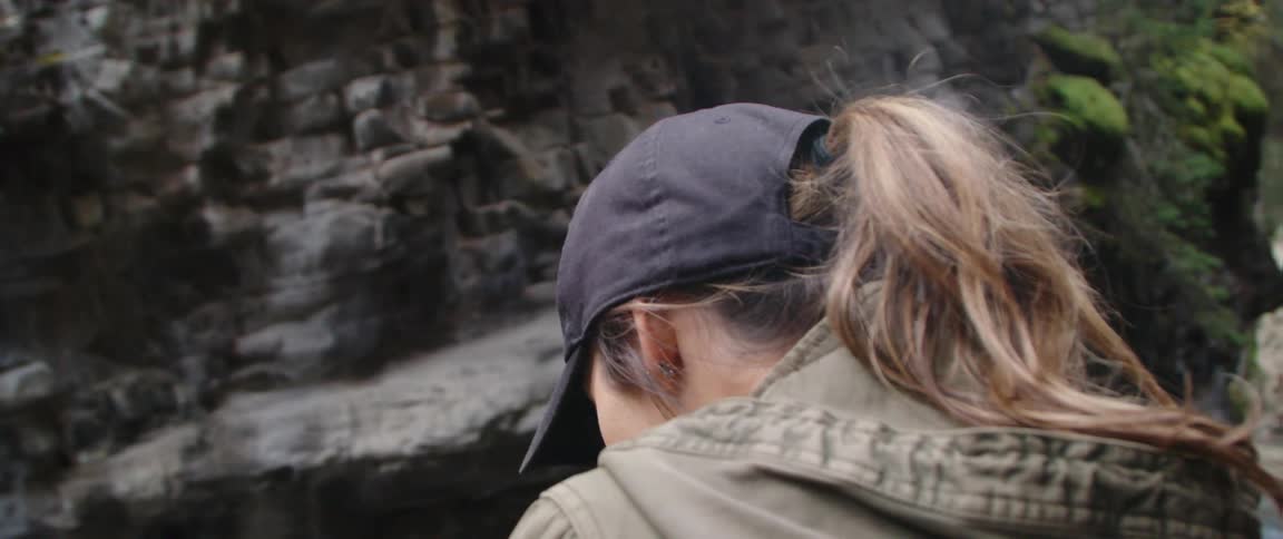 A woman watches the stream by the forest
