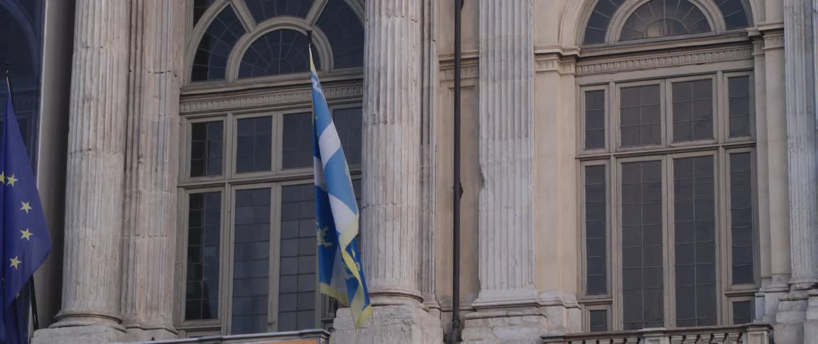 Two flags hang on the stone buildings