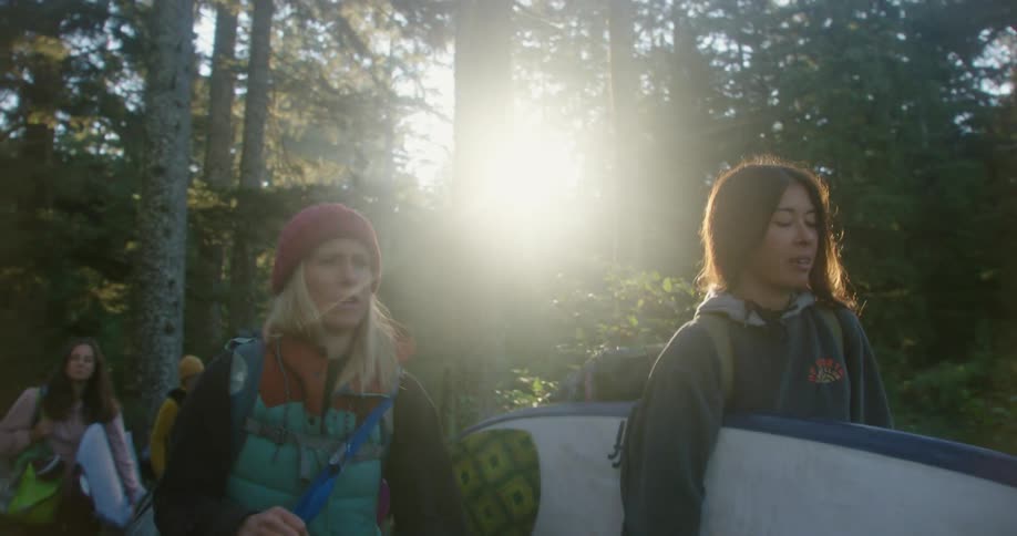 A group of surfers with backpacks walks in the woods