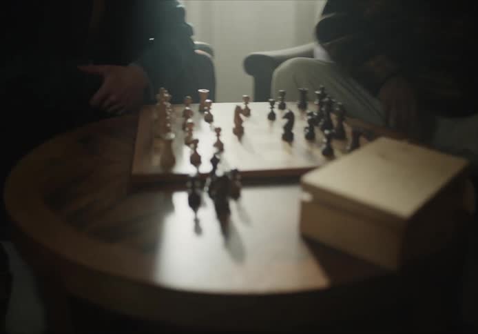 Two men are playing chess at a small table