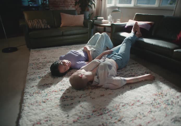 Two women lay on the rug talking