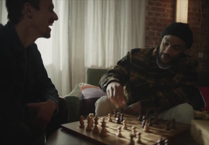 Two men are sitting indoors and playing a game of chess