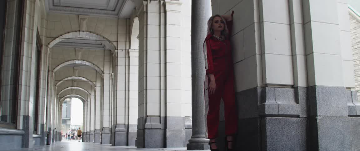 A woman is posing in a red track suit under the arches
