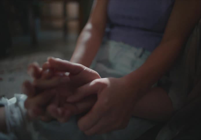 Mother holds hands with daughter as they sit on floor