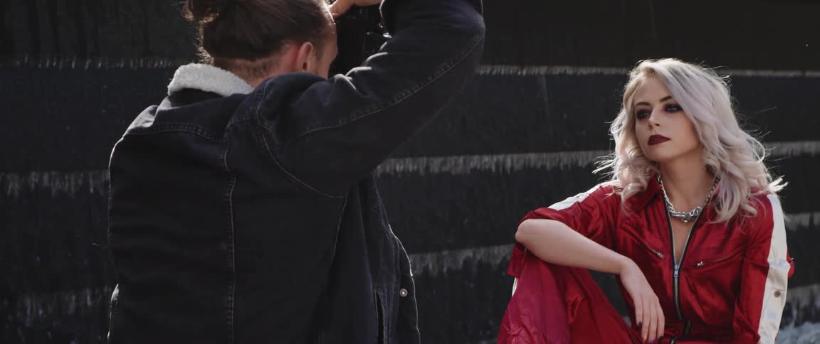 A photographer takes photos of a woman as she poses in front of a fountain