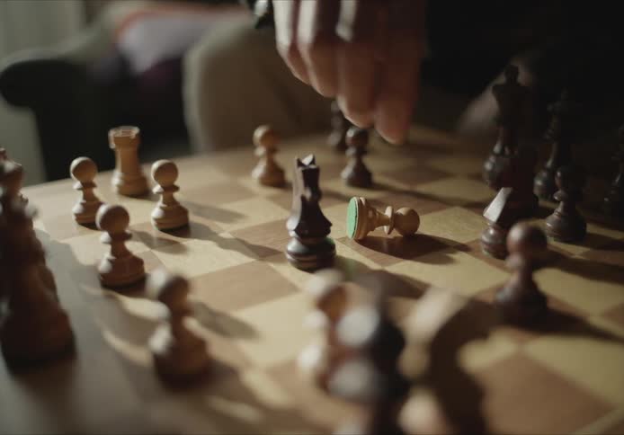 A chess player uses a knight to take a pawn on a wooden chess board