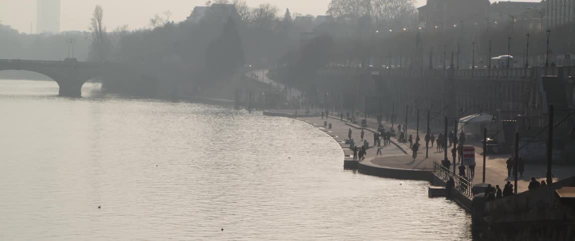 The people walk on the sidewalk near the water