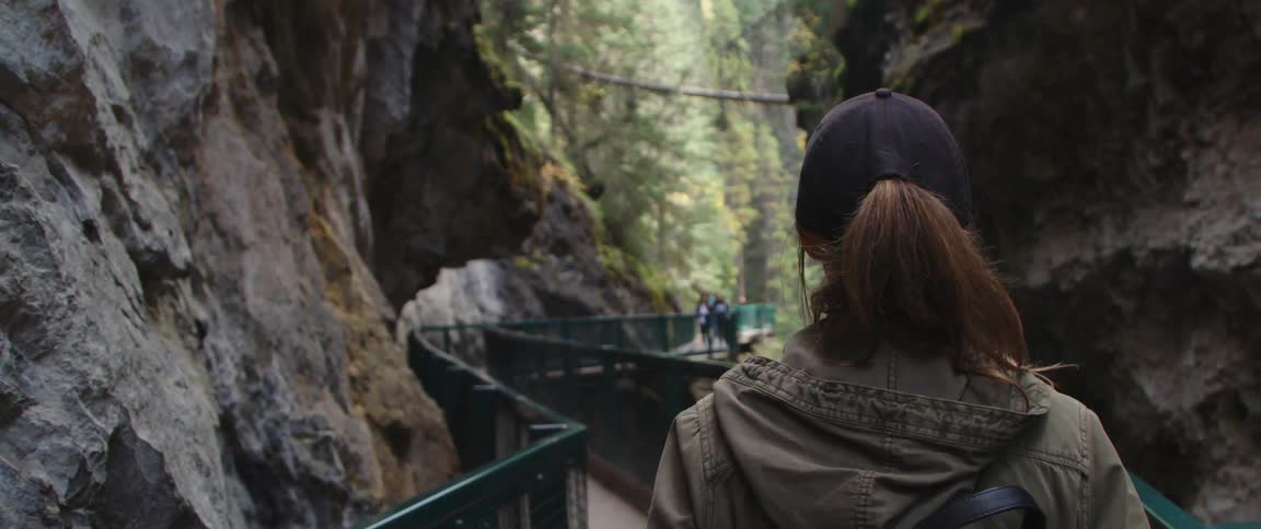 Woman walking on a bridge through a canyon in the mountains