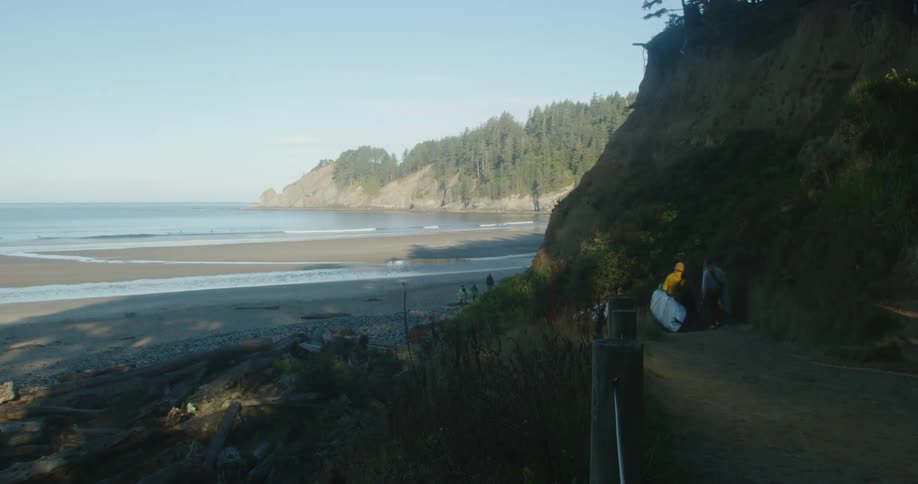 Group of women carriyng surfboards on a dirt road close to the ocean at morning