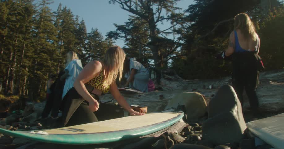 Group of women gearing up for surfing on a forest at morning