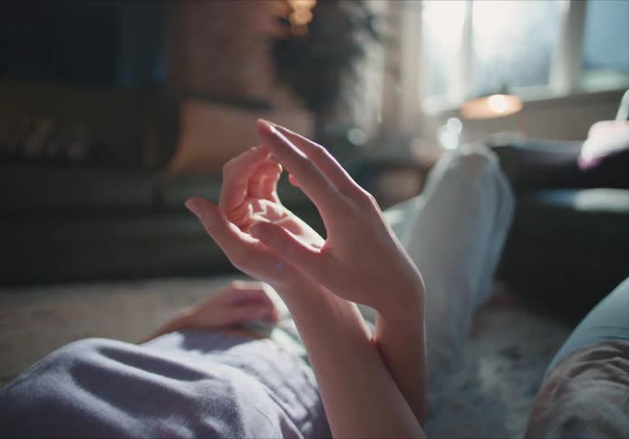 Couple lies on their backs on living room floor holding hands