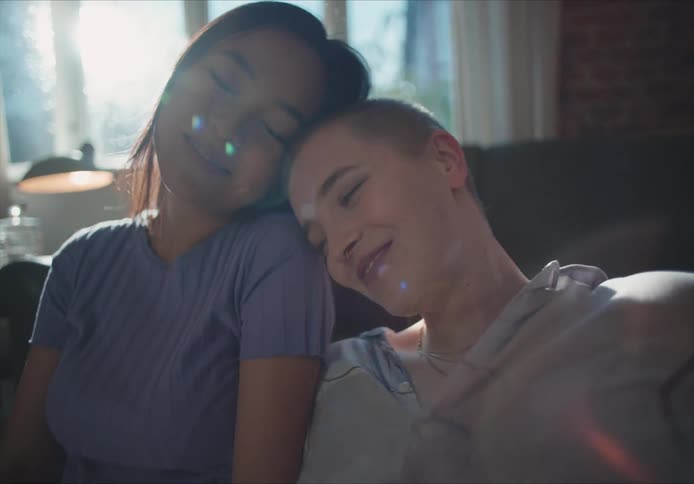 Young couple looking at each other smiling and laughing while cuddling at home in the morning