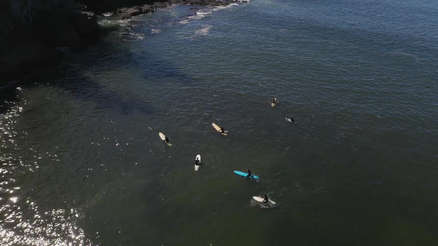 Aerial of surfers sitting on their surfboard in the ocean
