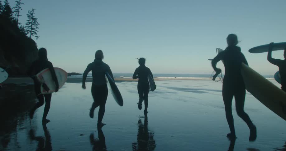 A crowd of people are at the beach with surfboards