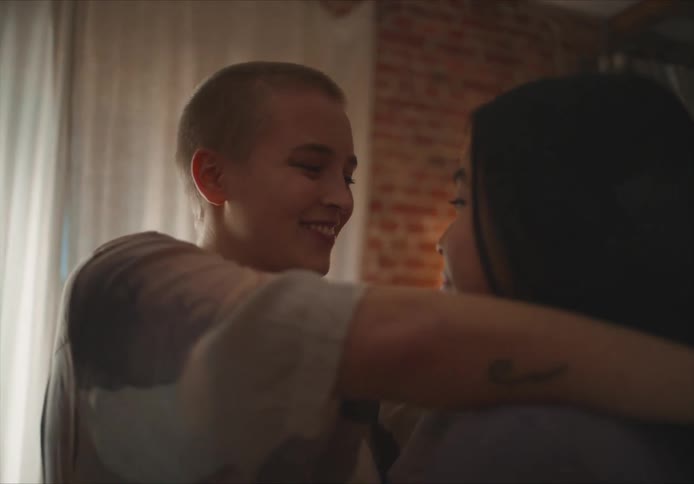 Couple with short and straight hair dances and lovingly looking into each others eyes in living room at home
