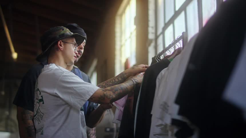 Two men are searching through a clothes rack in the store