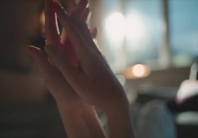 Two people hold hands in front of window