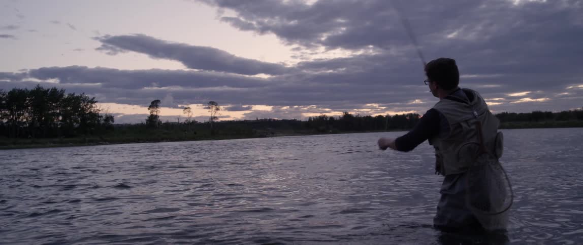 A man is fly fishing at sunset