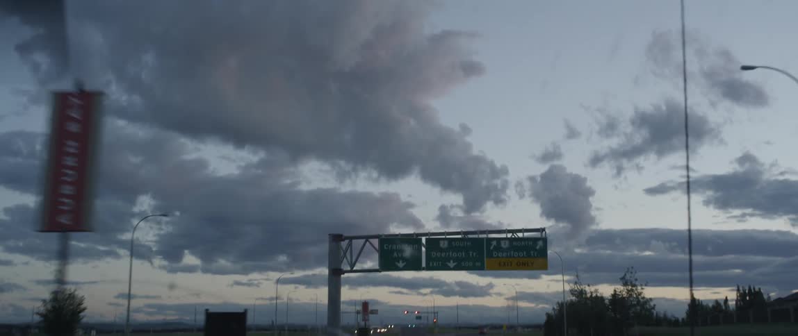 Driving under a street sign near sunset