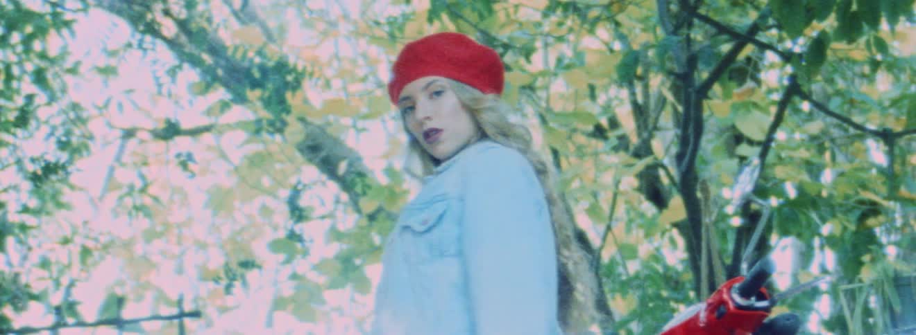 Blonde model wearing beret spins around and poses against motorcycle