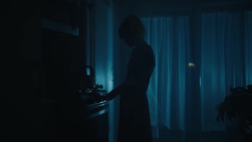 Silhouette of a woman warming water in the kitchen at night