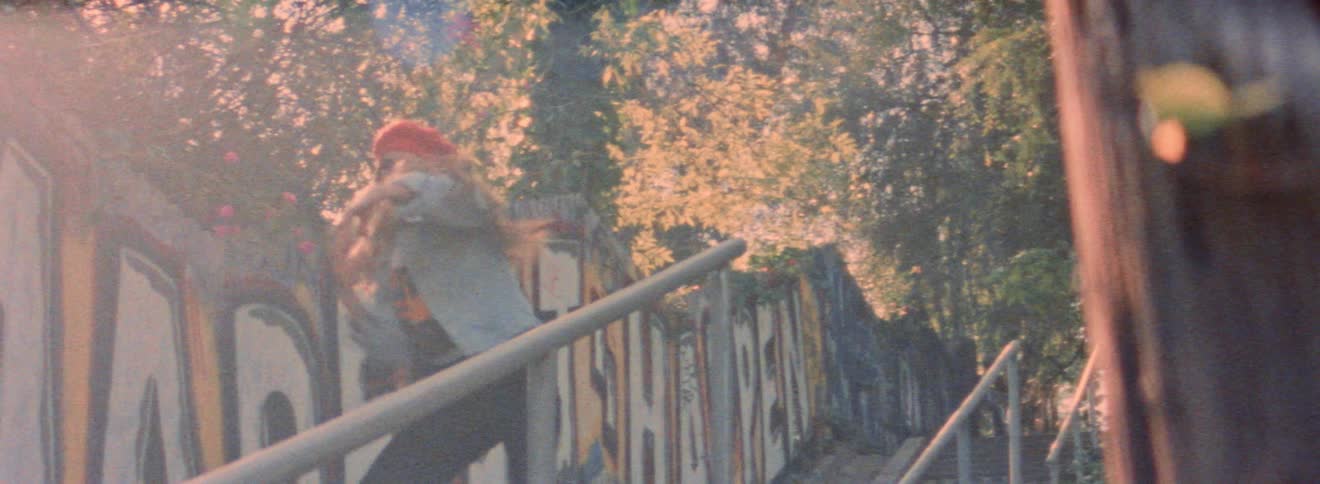 A girl dances hip hop moves while near a graffiti covered wall
