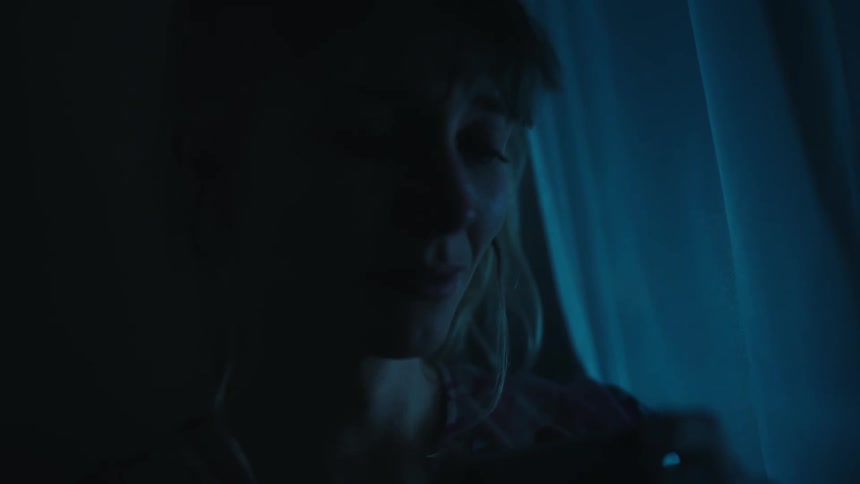 A blonde haired woman is sitting alone in the dark crying