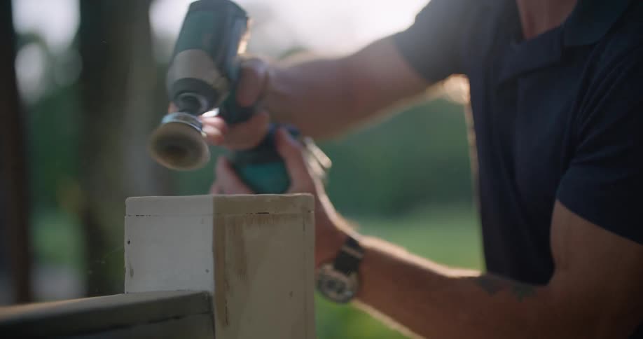 An employee brushing a piece of wood with a drill