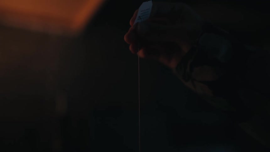A man stands outside at night and pulls up on a string