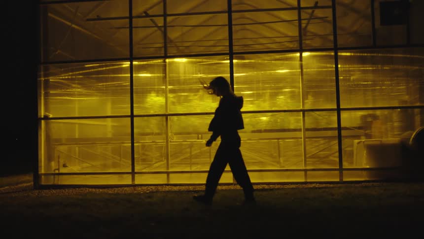 A woman walks through a dark room in a warehouse
