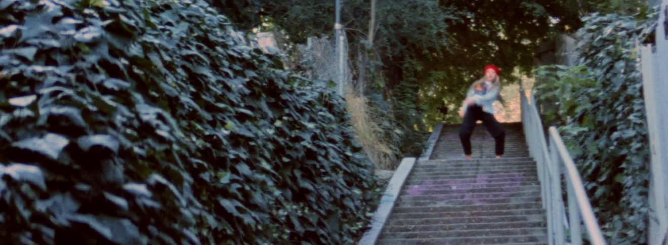 Blonde woman wearing denim jacket and red hat dancing on the stairs outdoor at morning