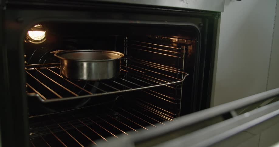Someone puts a pan in an oven and closes the door