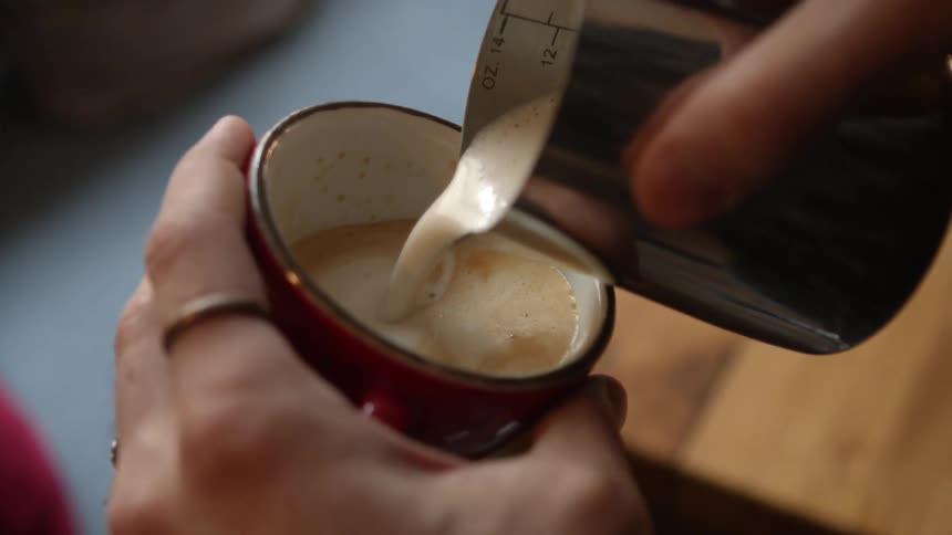A person pours cream in their drink