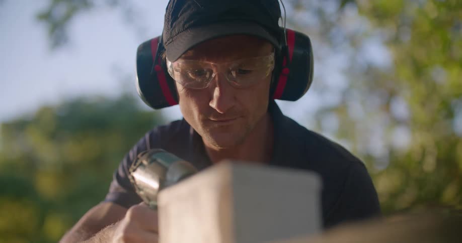 A man is sanding a wooden box outside