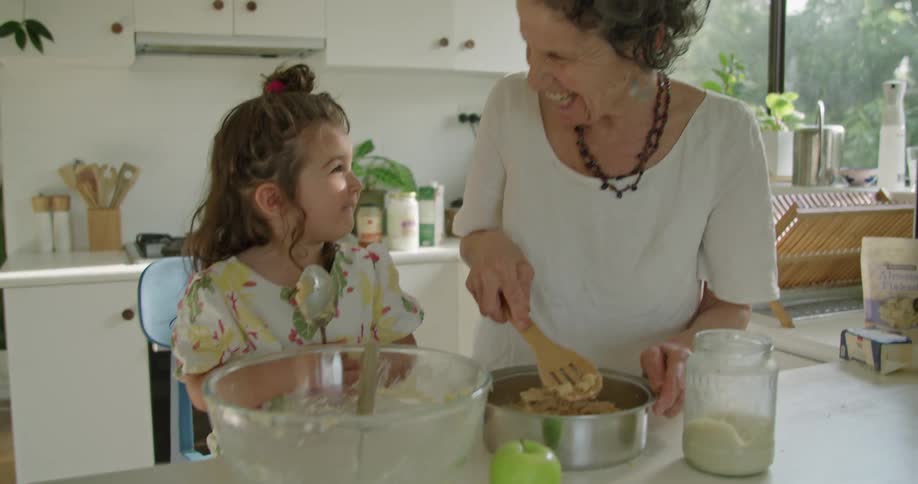 Grandmother and granddaughter smile as they cook together