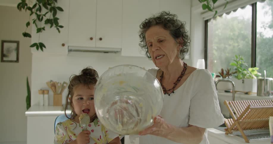 A grandmother is making food with her granddaughter