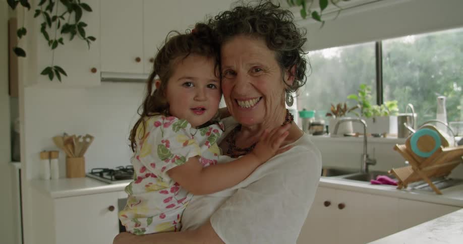A grandmother holds her granddaughter and poses smiling