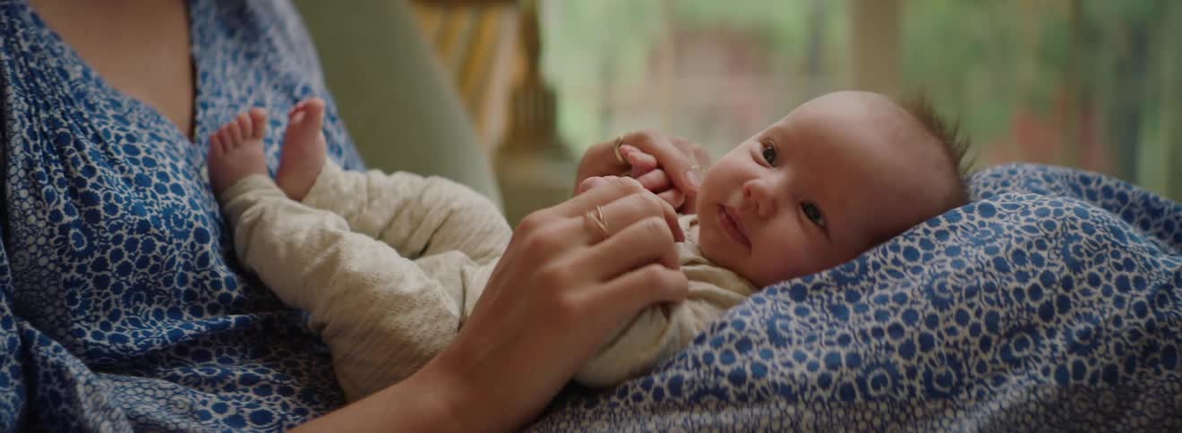 A mother is caressing the cheek of her baby with her finger