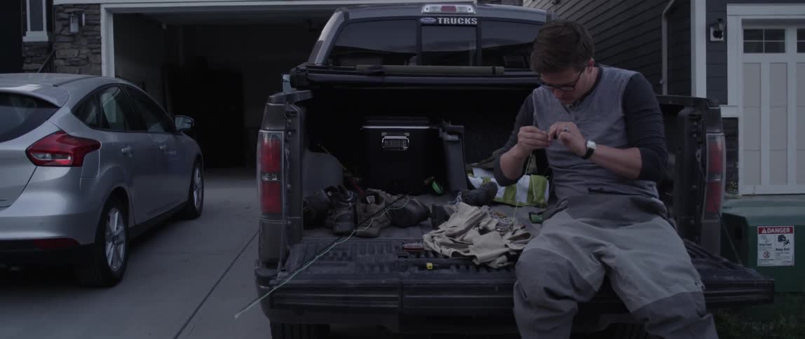 A man is working with his fishing equipment on the back of a truck