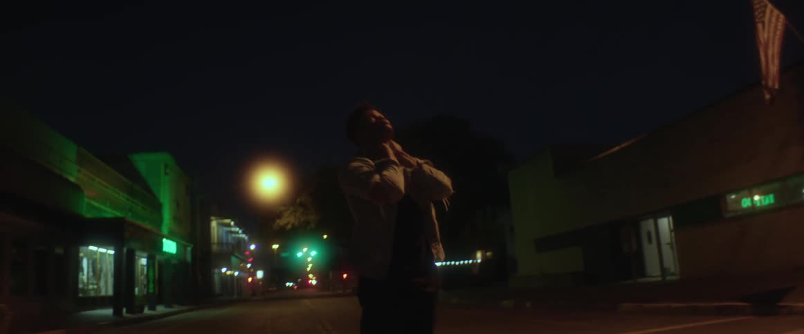 A man grabs his head while standing in the street