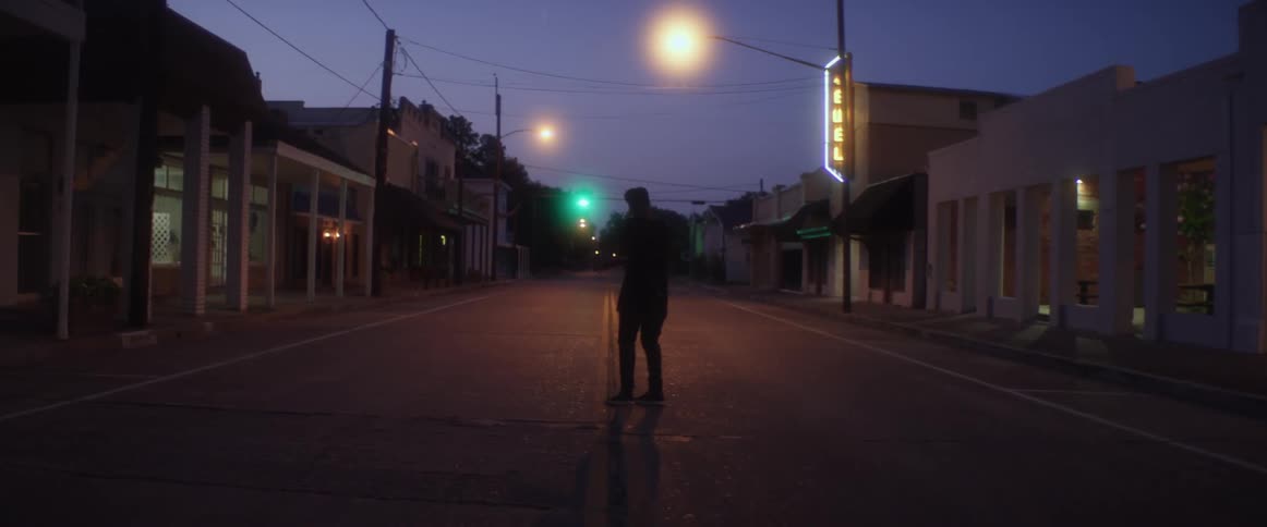 A person is dancing on a street during the night
