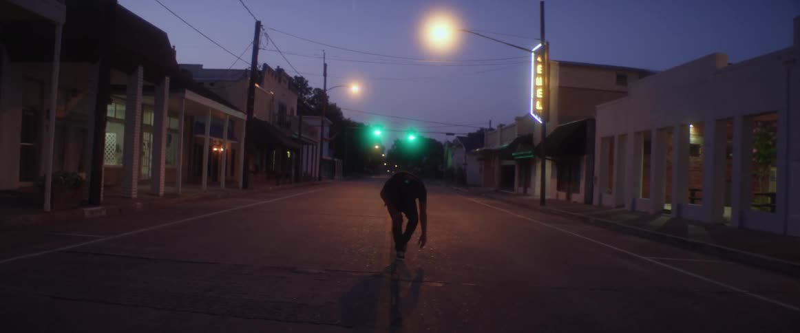 A man is dancing in the middle of a street in a small town at night