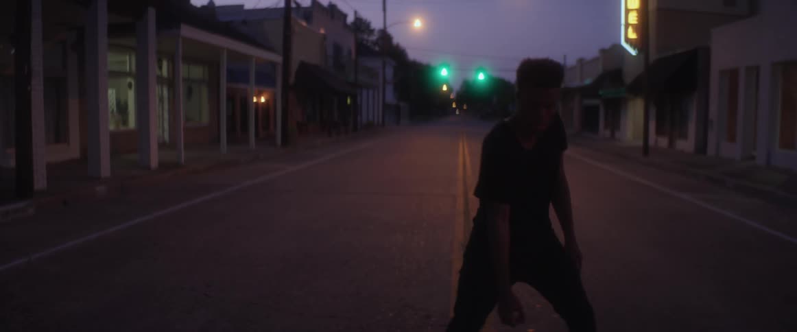A man is standing in a road and dancing at night