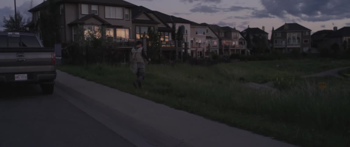 A man walks past a car on to a lawn
