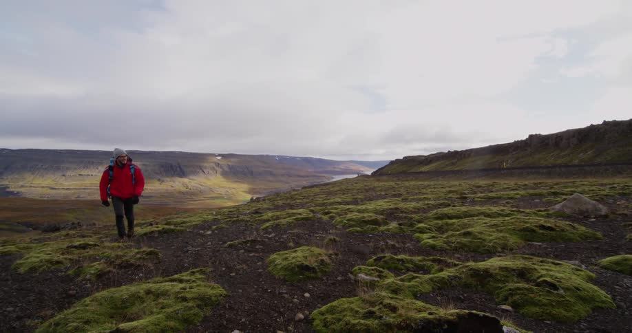 A man is hiking uphill on a cloudy day