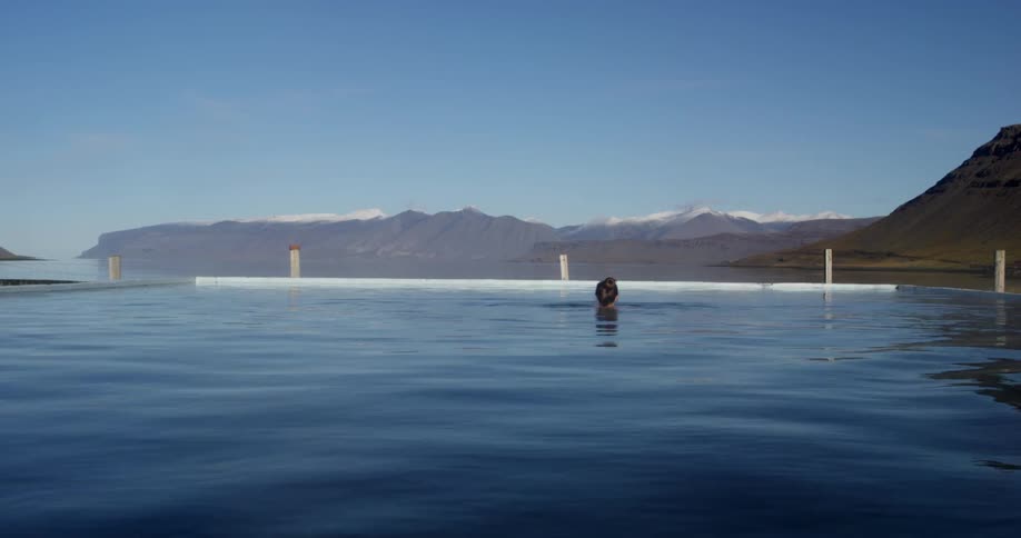 A woman is in a pool on a sunny day