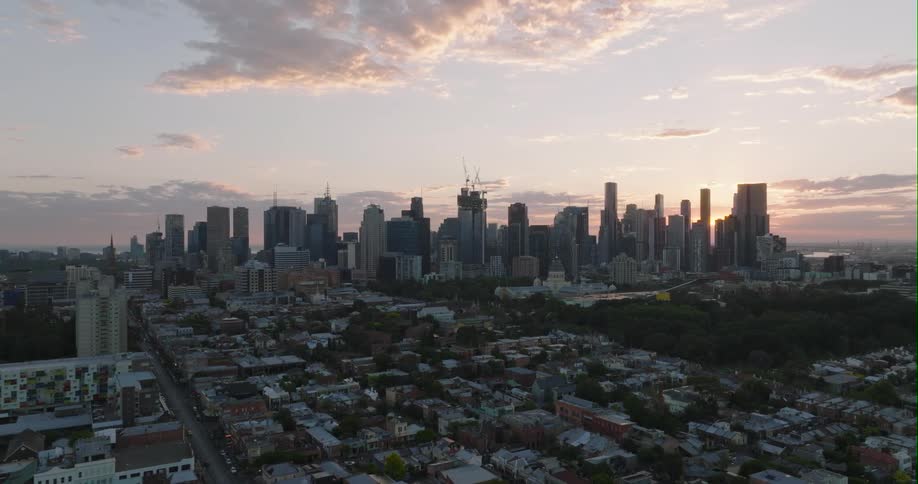 Sun is shining through buildings and skyscrapers of a city skyline at dawn