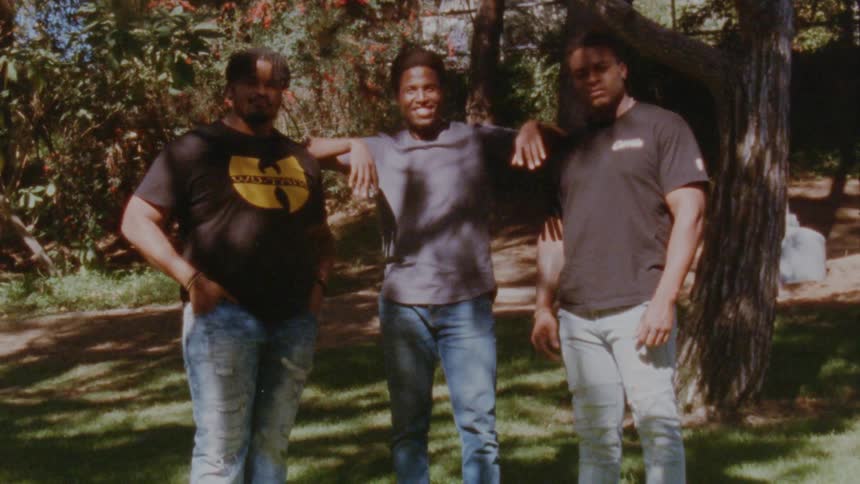 Three men are posing in the yard