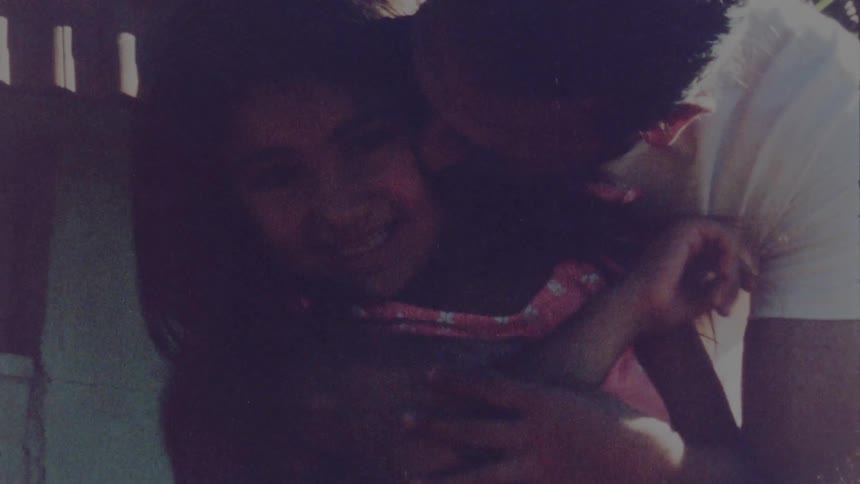 A little girl laughs as her dad hugs and squeezes her